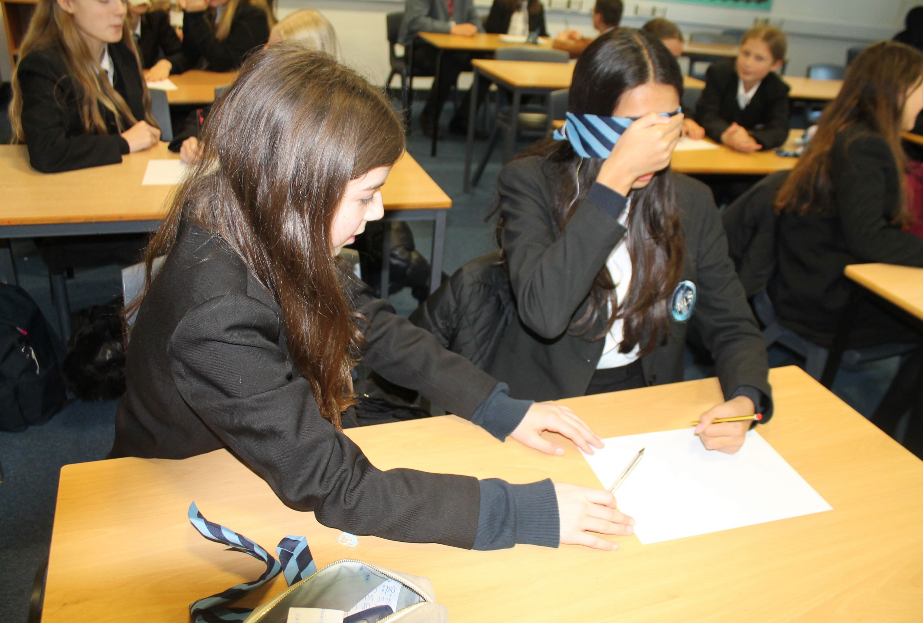 Two students taking part in events in the oracy day   - one drawing blindfolded guided by another student 