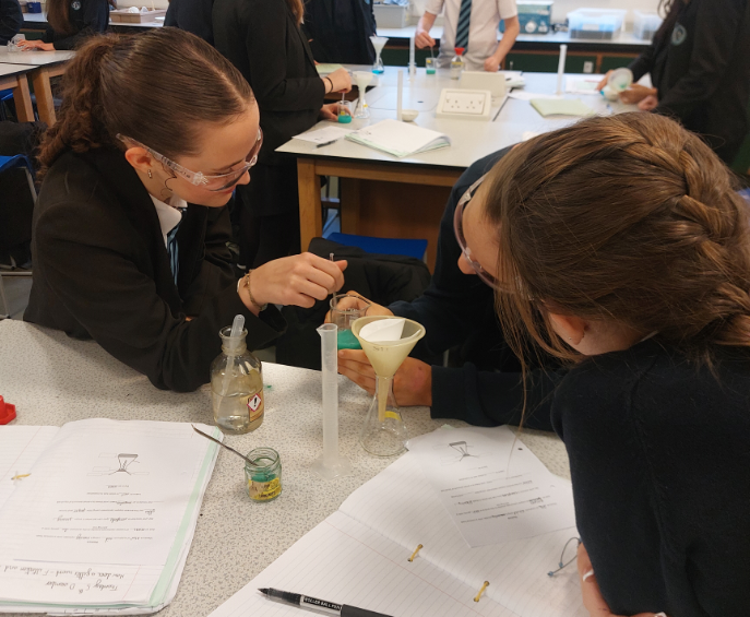 Two students conducting a practical on filtration and crystallisation