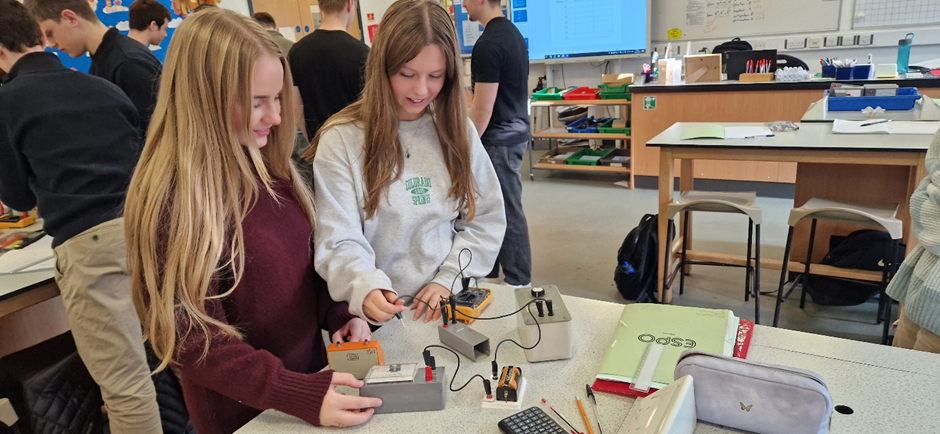 Two students in a  science lab investigating the processes of charging and discharging capacitors