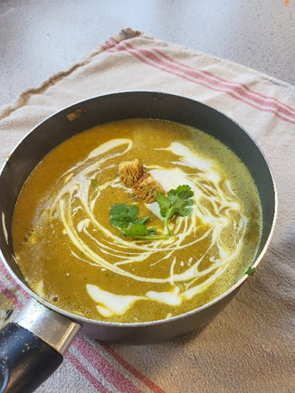 A pot of soup with croutons and parsley