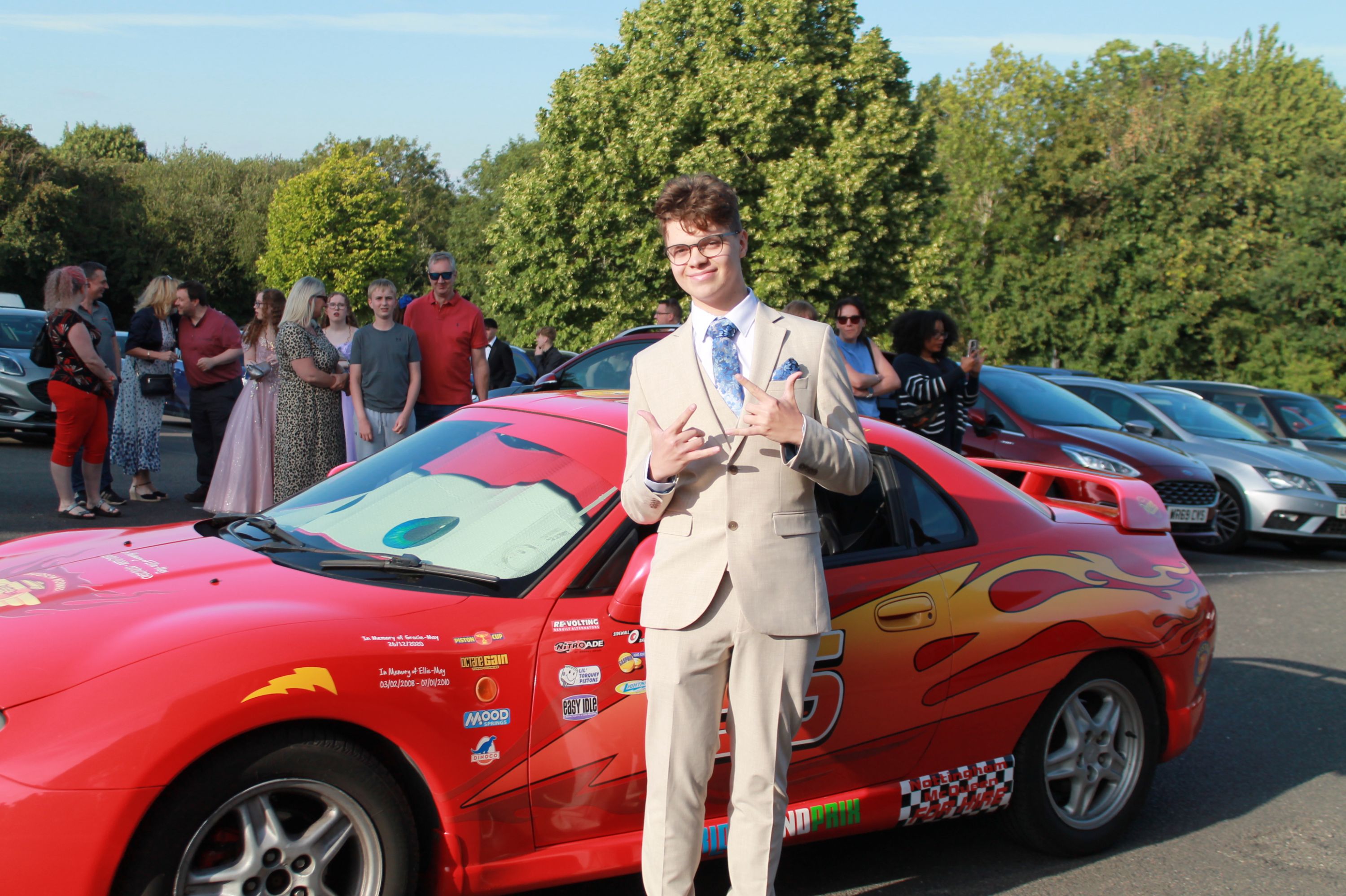 a student at prom standing by a red car