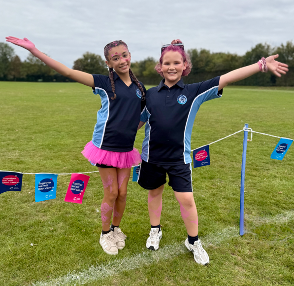 two students in PE kit posing at the race for life event