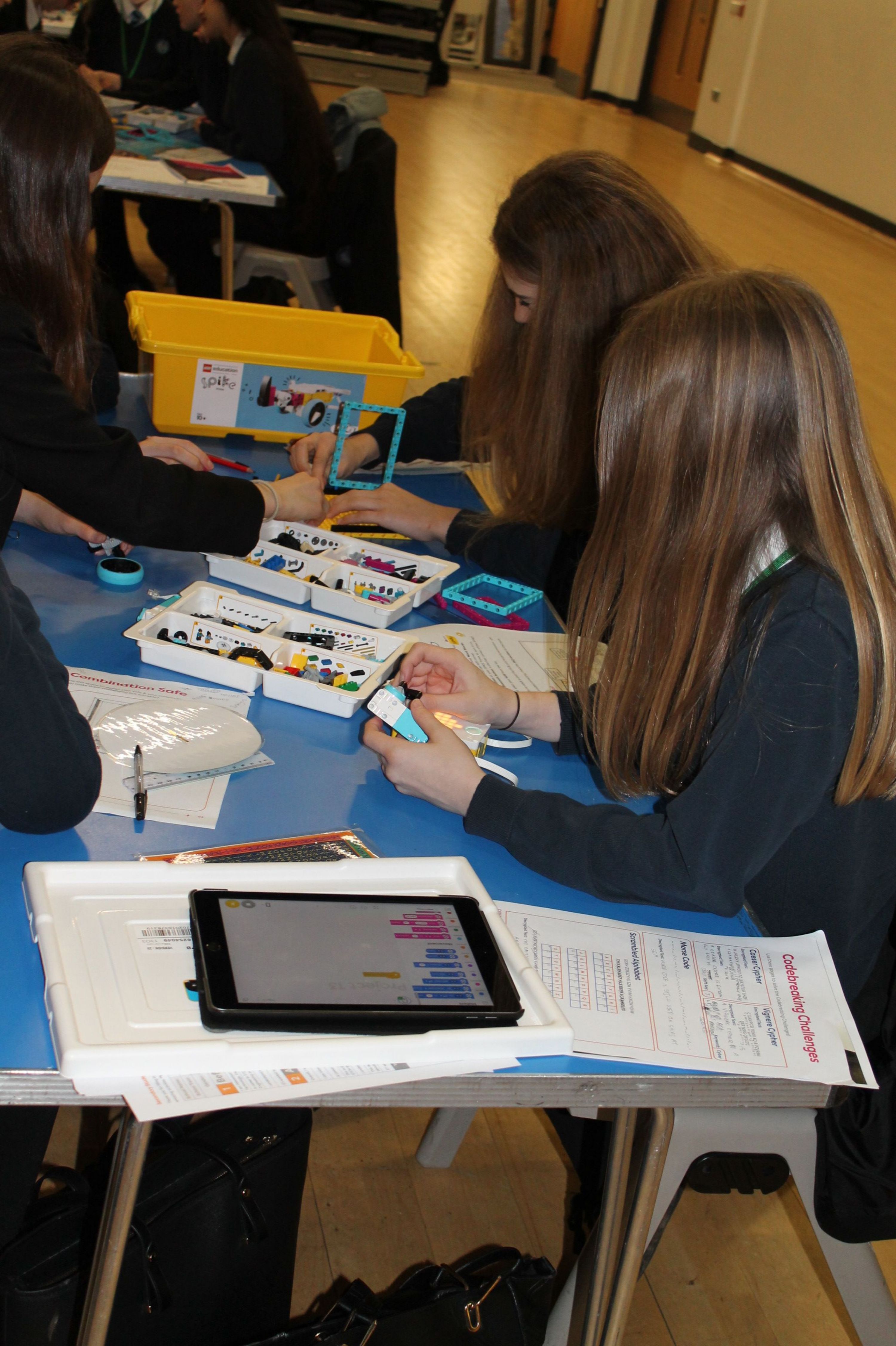 three girls sitting at a table building a model