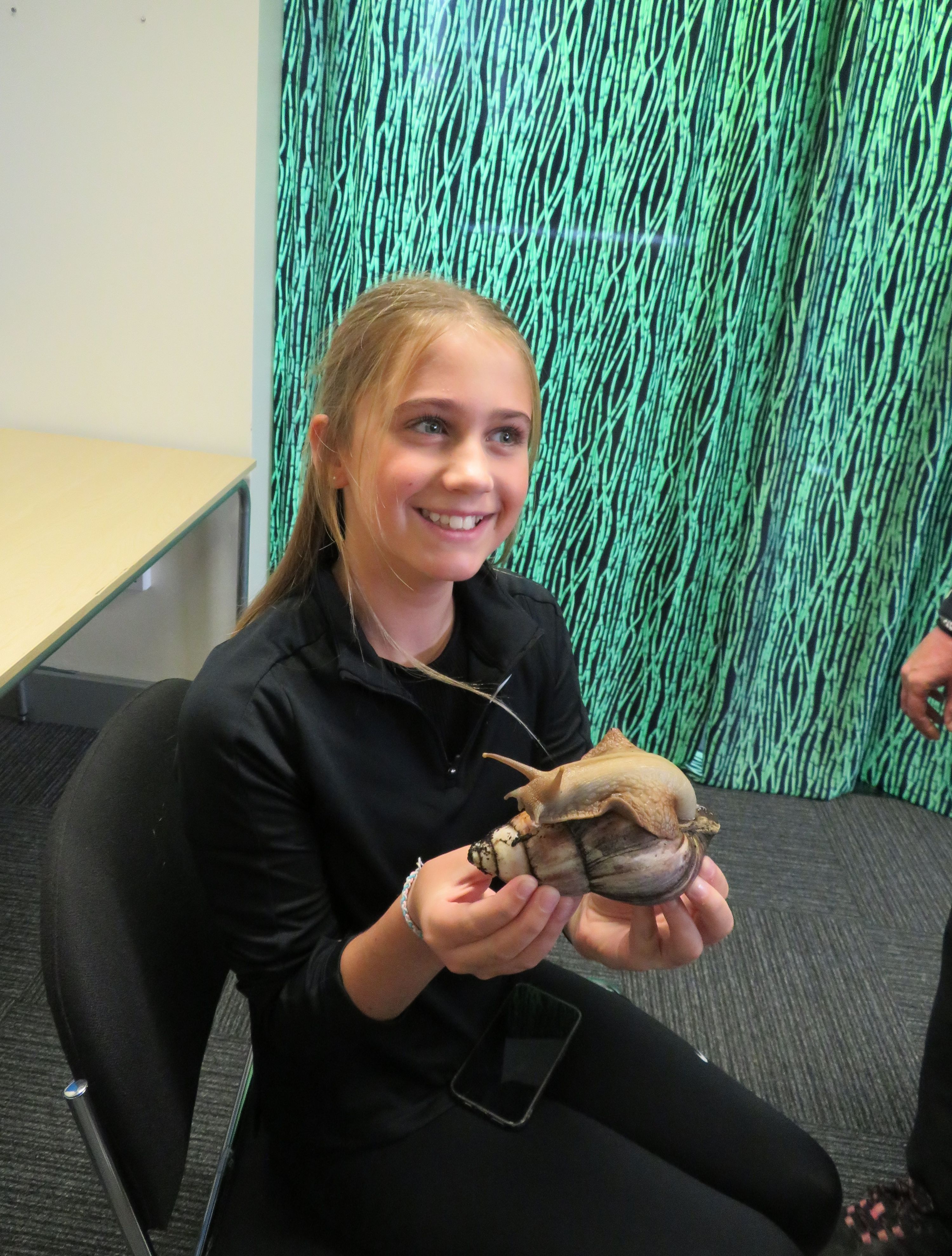 A smiling student holding a giant land snail