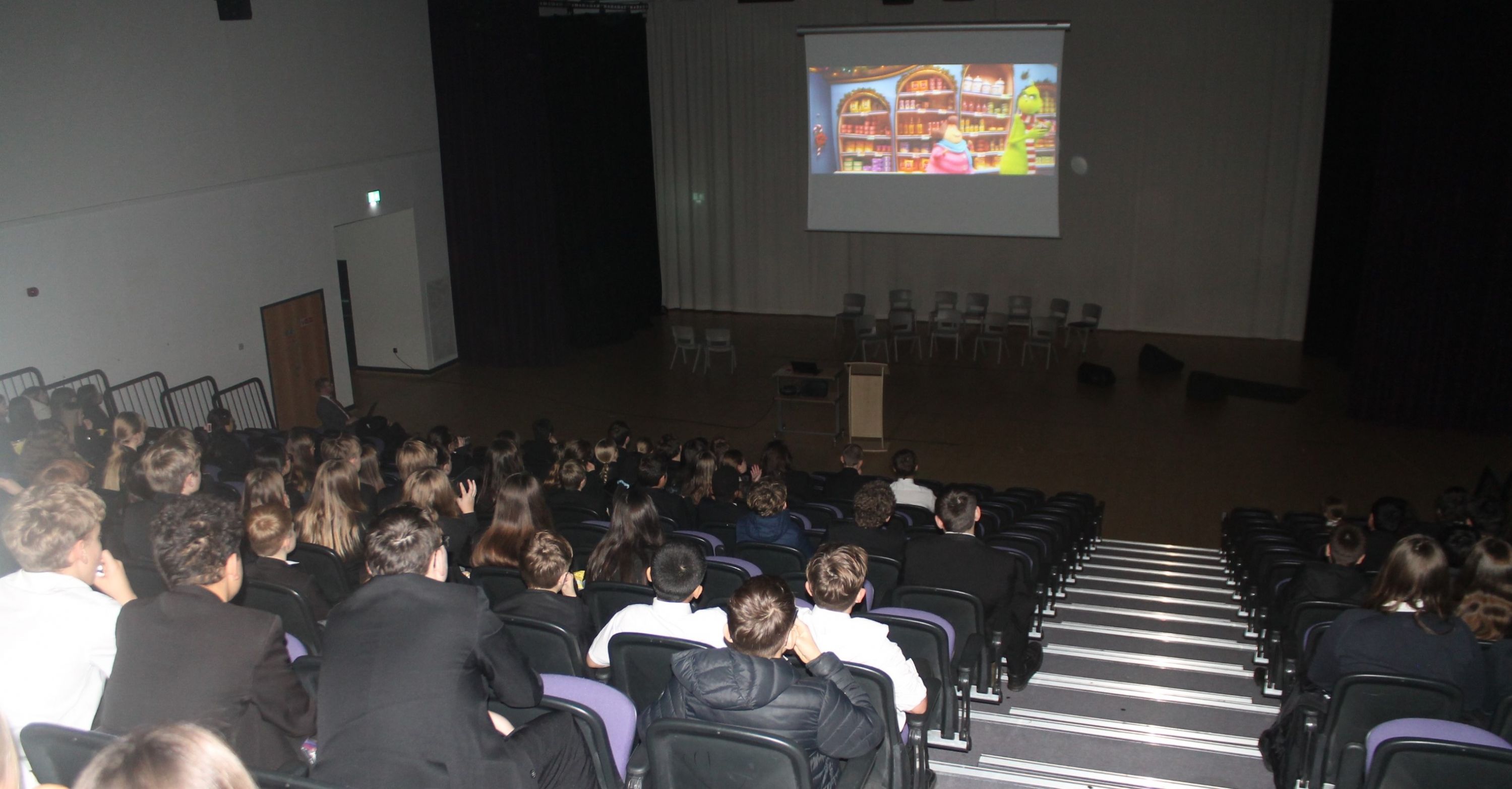 A group of seated students in the school Theatre watching a Christmas film 