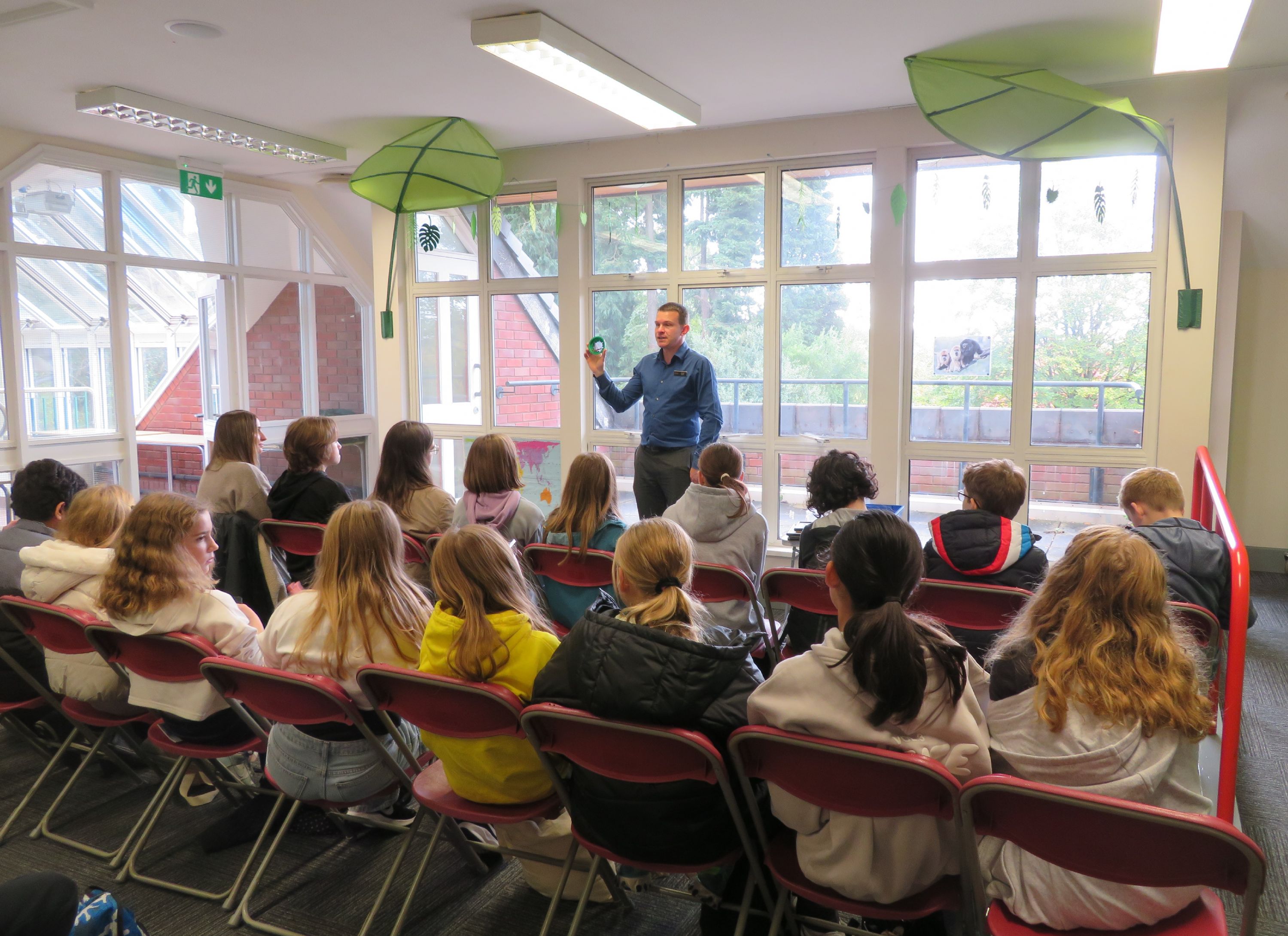 A group of seated students listening to a talk about rainforests and exotic creatures