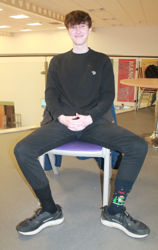 One student sitting on a chair showing his odd socks